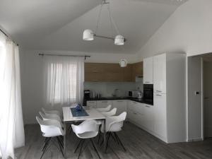 a white kitchen with a table and white chairs at Apartments Plavi&Žuti in Zaboric