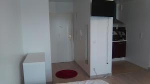 a white kitchen with a refrigerator and a red rug at Appartements Sully in Mantes-la-Jolie