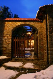 una entrada a un edificio de piedra con una puerta en la nieve en Argyriou Wine Tasting Guest House, en Polydrosos
