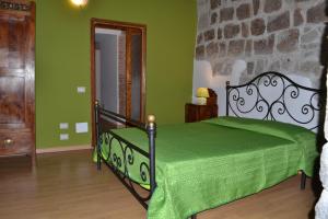 a bedroom with a bed with a green comforter at La Torre Nel Borgo in Viterbo