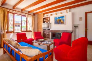 a living room with red chairs and a bed and a tv at Villa Xavier in Can Picafort