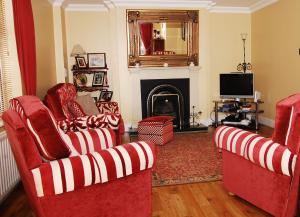 a living room with two red chairs and a fireplace at Nephin Lodge in Westport