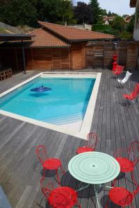una terraza con mesa y sillas y una piscina en la Palisse en Peaugres