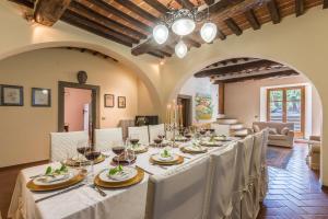 una sala da pranzo con un lungo tavolo con tovaglia bianca di Palazzo Rosadi by PosarelliVillas a Monterchi