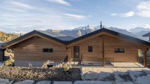 une maison en bois avec des montagnes en arrière-plan dans l'établissement Huwetz 2, à Bettmeralp