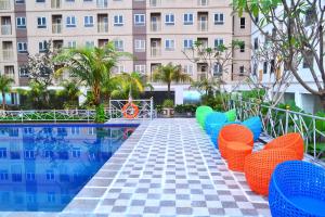 a row of chairs by a pool in front of a building at Titanium Express HomTel in Jakarta