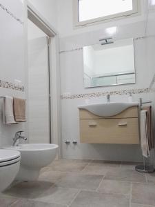 a bathroom with a sink and a toilet and a mirror at Il profumo del mare in Marina di Mancaversa