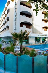 un hôtel avec une piscine en face d'un bâtiment dans l'établissement Hotel Vittoria, à Riccione