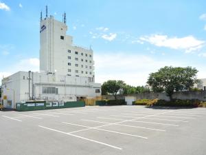 un estacionamiento con un gran edificio blanco en Hotel Route Tsukuba, en Tsukuba