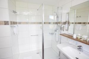 a white bathroom with a shower and a sink at Prinz-Luitpold-Bad in Bad Hindelang