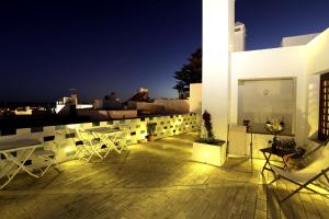 a balcony with white chairs and tables on a building at Hostal El Alojado de Velarde in Conil de la Frontera