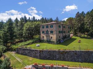 an old stone building on a grassy field with trees at Palazzo Rosadi by PosarelliVillas in Monterchi