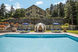 a swimming pool with chairs and umbrellas and a building at Palazzo Rosadi by PosarelliVillas in Monterchi