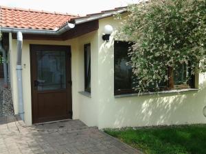 ein weißes Haus mit einer braunen Tür und einem Baum in der Unterkunft Ferienhaus Waldblick in Sangerhausen