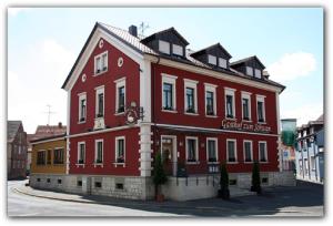 un gran edificio rojo con un cartel en él en Gasthof zum Schwan, en Kürnach