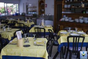 a dining room with tables and chairs with yellow table cloth at Hotel Mimosa in Spotorno +60 photos