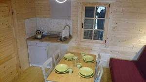 a kitchen with a wooden table with chairs and a sink at Domki Przy Orzechu in Lubin