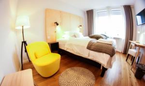 une chambre d'hôtel avec un lit et une chaise jaune dans l'établissement Hemma rooms by IKEA, à Zbąszyń