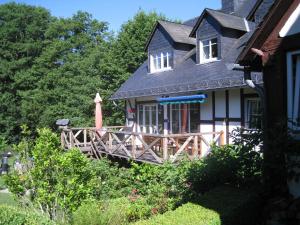 a house with a porch and a wooden deck at Romantikmühle Heartlandranch in Krummenau