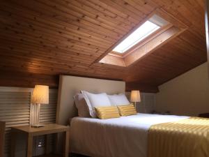 a bedroom with a large bed with a skylight at Populo Beach Attic in Ponta Delgada