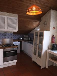 una cocina con armarios blancos y una lámpara de araña en Populo Beach Attic, en Ponta Delgada