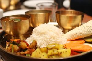 a plate of food with rice and vegetables and gold spoons at Rock Garden Resort in Pokhara