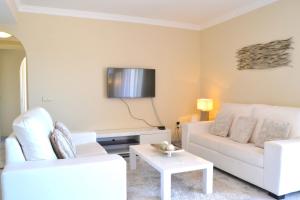 Dama de Noche Penthouse RDR110 في مربلة: غرفة معيشة مع كنبتين بيضاء وتلفزيون