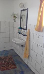a white tiled bathroom with a sink and a mirror at Capricorn Restcamp in Rietoog