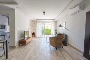 sala de estar con paredes blancas y suelo de madera. en MalagaSuite House Pool, en Santa Fe de los Boliches