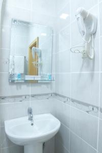 a white bathroom with a sink and a mirror at Hotel Alma Ata in Zhosaly