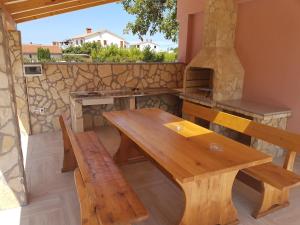 drewniany stół i ławki przed kamiennym piecem w obiekcie Vacation house "Viola" w Fažanie