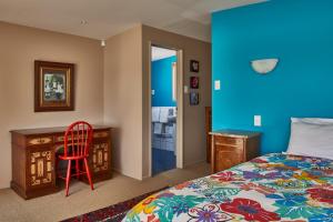 a bedroom with a bed and a desk and a red chair at Akaroa on the Beach in Akaroa