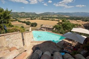 a pool with an umbrella and a person swimming in it at La Bastiglia in Spello
