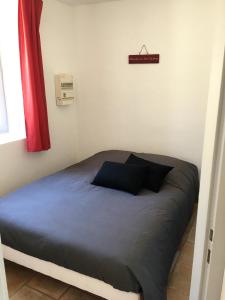 een bed in een kleine kamer met een bord aan de muur bij Appartement Paisible in Fontaine-de-Vaucluse