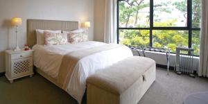 a bedroom with a bed and a large window at The Glen Apartments in Cape Town