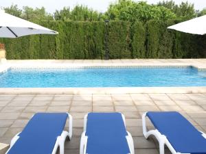 ポリェンサにあるCan La Villaのスイミングプールの隣に青い椅子2脚とパラソルがあります。