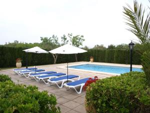 a group of lounge chairs and umbrellas next to a pool at Can La Villa in Pollença