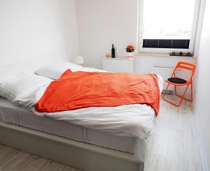łóżko z pomarańczowym kocem w pokoju w obiekcie Sunshine Rooms w Gdańsku