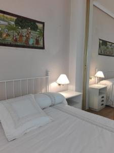 a white bedroom with a bed and a table with lamps at Casa Bellavista in Segovia