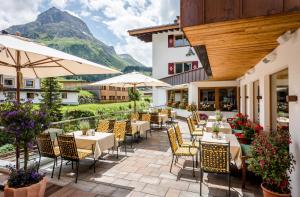 un patio con tavoli e sedie con montagne sullo sfondo di Hotel Auenhof a Lech am Arlberg