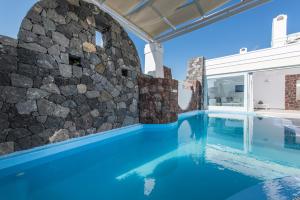 a pool with a stone wall next to a house at Secret Earth Villas - Santorini in Kamari
