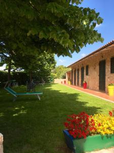 einen grünen Garten mit Blumen und einem Gebäude in der Unterkunft Agriturismo Poggio del Drago in Montemerano