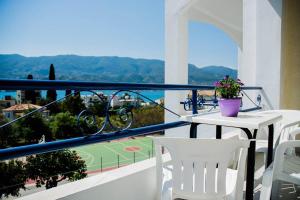 a balcony with a table and chairs and a tennis court at Christina Perlia Studios in Poros