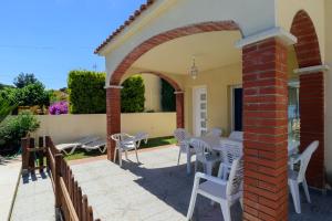 a patio with white chairs and a brick archway at Costabravaforrent Ricardell in L'Escala