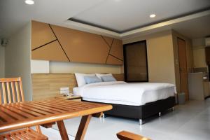 ein Schlafzimmer mit einem großen Bett und einem Holztisch in der Unterkunft TUCK Me iN in Chiang Mai