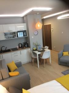 a kitchen and a living room with a table and a couch at Apartament Nowa Motława & SPA in Gdańsk