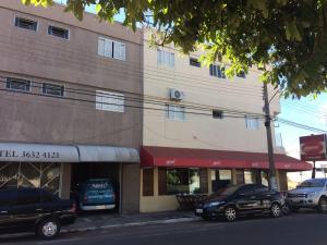 a building with two cars parked in front of it at Roda Viva Park Hotel in Jales