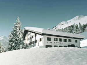 莱赫阿尔贝格Hinterwies – Ski In / Lodge / Dine的雪地中的一座建筑,有圣诞树