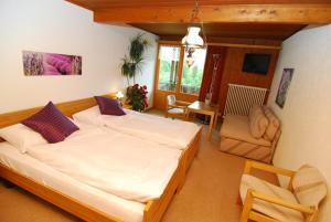 a bedroom with a large bed and a living room at Hotel Rothorn in Schwanden