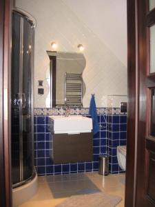 bagno piastrellato blu con lavandino e specchio di Domki pokoje pod Wierzba a Sarbinowo